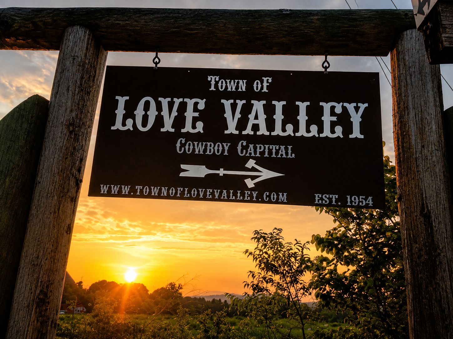 Town of Love Valley 'Cowboy Capital' sign silhouetted against a golden sunset